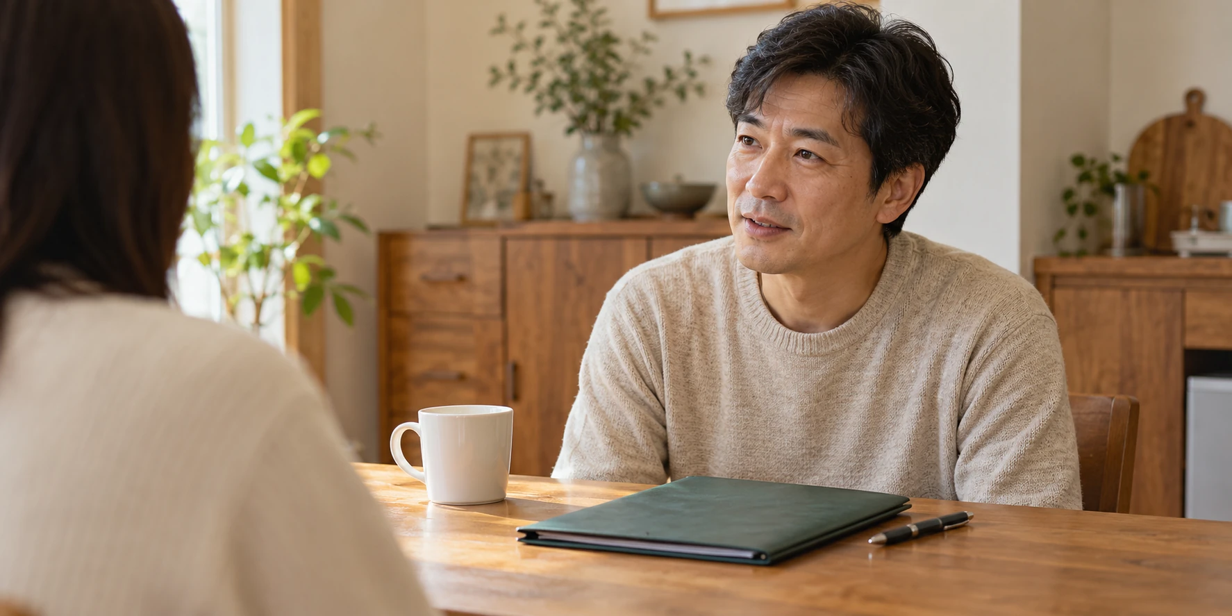 A middle-aged man talking calmly with a family member at home, with a folder of records on the table